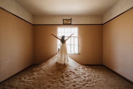 happy young woman in abandoned desert house enjoying playing with white dressの写真素材
