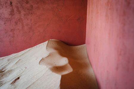 Closeup view of sand patterns and texture next to pink walls of an old house on rock sandstoneの写真素材