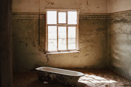 moody atmosphere photo with, Old bathtube in the ruins of the mining town named Kolmanskop located in the Namib desert near Luderitz in Namibiaの写真素材