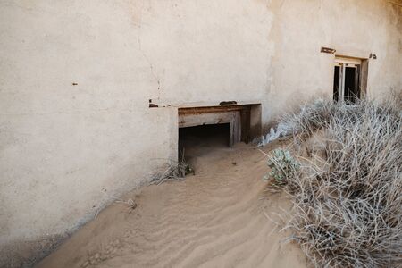 symbolic photo for decay, death and time passing when desert sand enters ruined building in Kolmanskop, Namibia, Africa - lots of copyspaceの写真素材