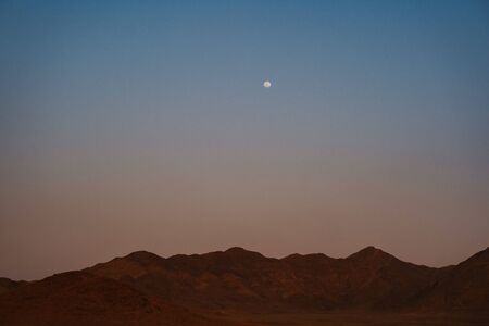 mesmeringing evening moon at NamibRand Naturreservat with mountains and desert sand and the moon in Namibia, Africaの写真素材