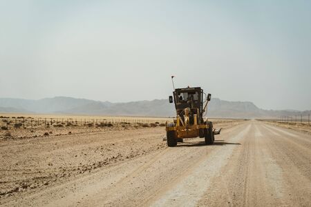 A bulldozer grader working on a gravel road in Namibia, Africaの写真素材