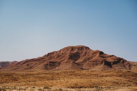 imposing red mountains and bald granite peak with blue sky, Damaraland, Naukluft national park, Namib Desert, Namibia, Southern Africaの写真素材