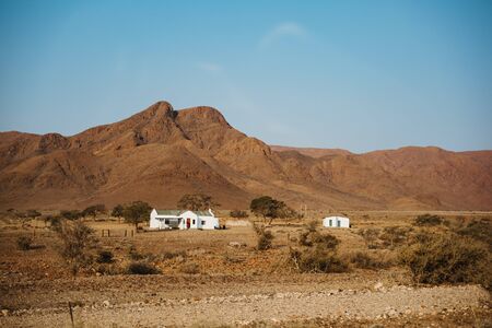 lonely farmers house in the desert of Namibia with mountains in backgroundの写真素材