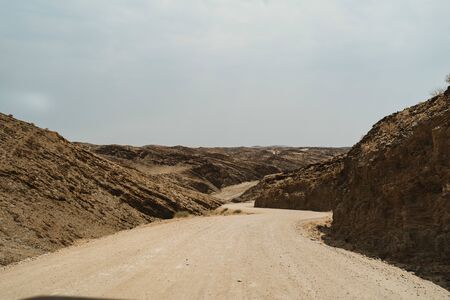 road through dry river in moon landscape with rocks, stones and mountainsの写真素材