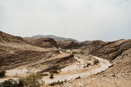 road through dry river in moon landscape with rocks, stones and mountainsの写真素材