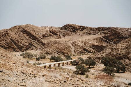 road through dry river in moon landscape with rocks, stones and mountainsの写真素材