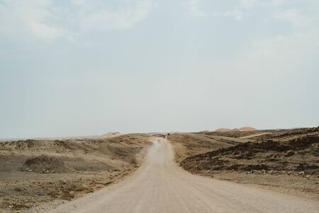 road through dead Moon Landscape with rocks, stones and mountainsの写真素材