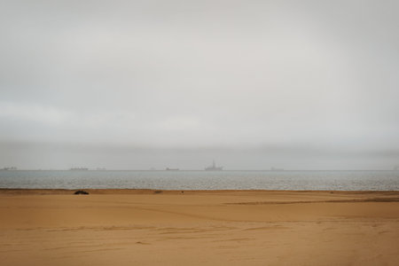 shore coast with oil tankers on the sea in bad weather with stormy clouds near city of Swakopmund in...