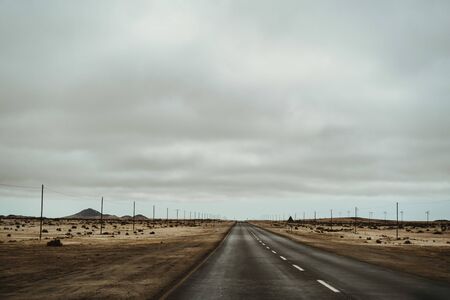 Electricity Pylons in dry desert mountains with dramatic sky, concept photo for future of electricity and climate changeの写真素材