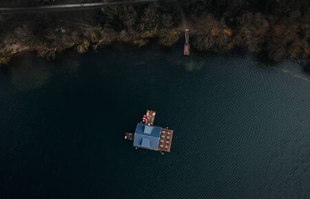 single houseboat on water of a lake surrounded by treesの写真素材