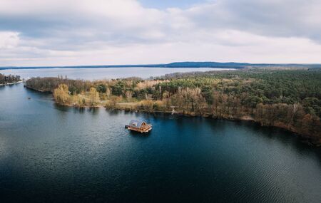 single houseboat on water of a lake surrounded by treesの写真素材