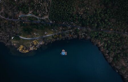 single houseboat on water of a lake surrounded by treesの写真素材