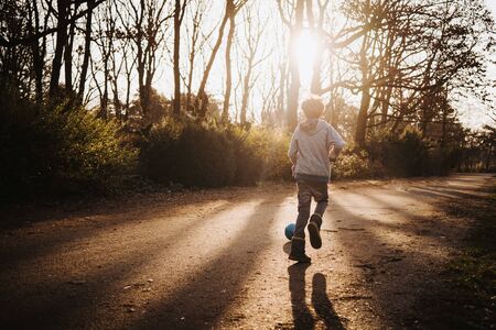 Little Caucasian boy playing soccer in forestの写真素材
