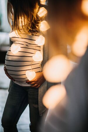 pregnant young woman holding her belly at homeの写真素材