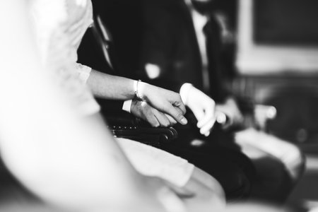 wedding couples hands holding at the cerenomy, sitting inside registry office