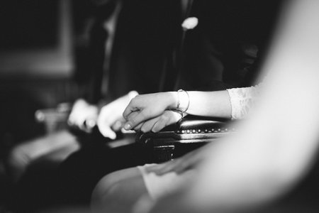 wedding couples hands holding at the cerenomy, sitting inside registry office