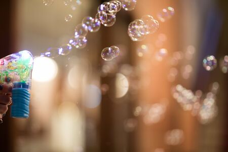 A mans hand uses a bubble gun to blow bubblesの写真素材