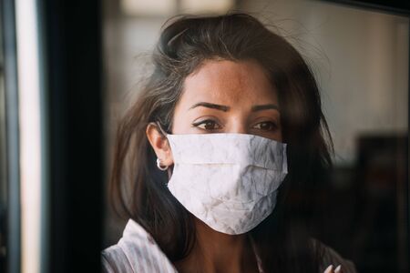 woman wearing selfmade protection mask at windowの写真素材