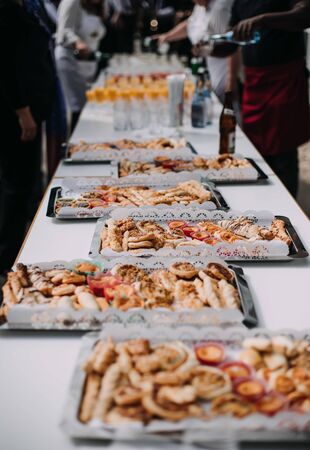 Salty and cheese bar of several kinds of cheese, grapes, olives and snacks decorated on vintage wooden table. Wedding or other holiday party outdoorsの写真素材