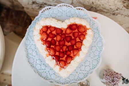 photo of a heart shaped strawberry cake on a tableの写真素材