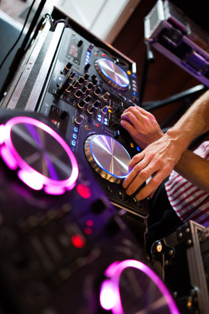photo of a dj playing on his mixer