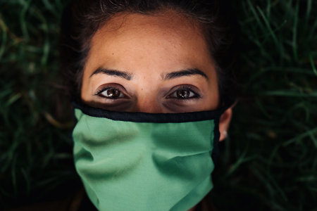 photo of a woman wearing a face mask lying in the grass