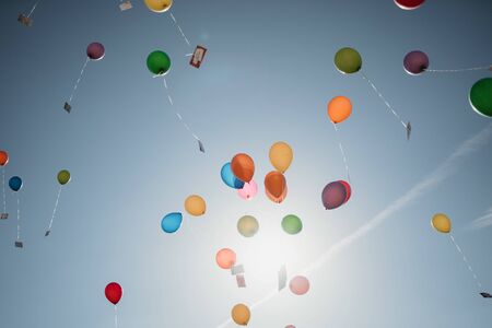 colorful helium balloons flying in the skyの写真素材