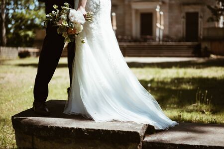 a bride with bouquet and the groom in the gardenの写真素材
