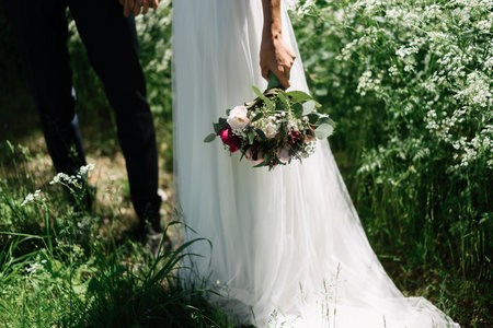 a bride with bouquet and the groom in the garden
