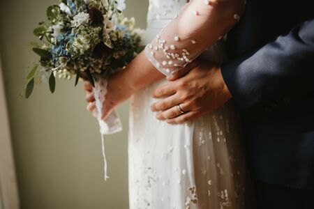 a wedded couple standing next to the windowの写真素材