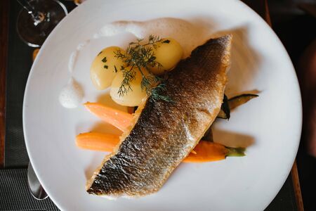 tasty fried salmon fish with potato, carrot and garlicの写真素材