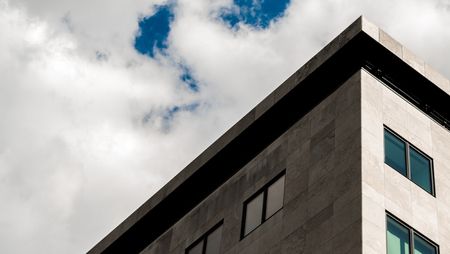 High contrast corner of a modern office building on a cloudy sunny dayの写真素材