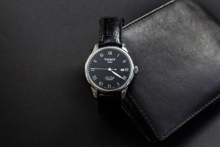 Budapest, Hungary - September 10, 2017: The Tissot Le Locle is a black leather watch with a black leather wallet on a dark gray background.のeditorial素材