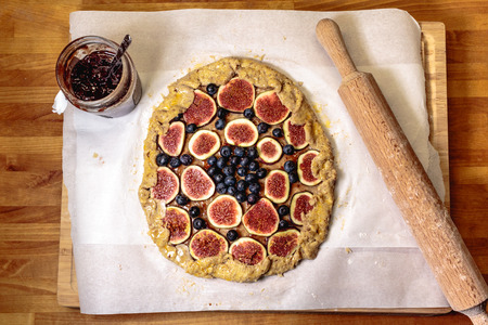 A french galette on a baking paper along with a rolling pin and a plum jamの写真素材