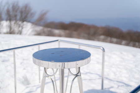 metal table and chair in the snow on the background of the mountains