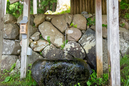 Water fall in a Japanese garden with a stone wall and a small shrineの写真素材