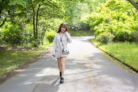 Young beautiful asian woman walking on the road in the park.の写真素材