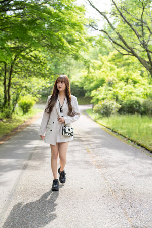 Beautiful asian woman in white coat walking in the park.の写真素材