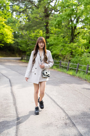 Beautiful young asian woman walking in the park with coffee cupの写真素材