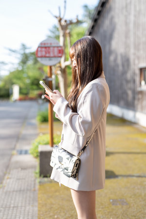 Young asian woman using smartphone in the street at summer day.の写真素材