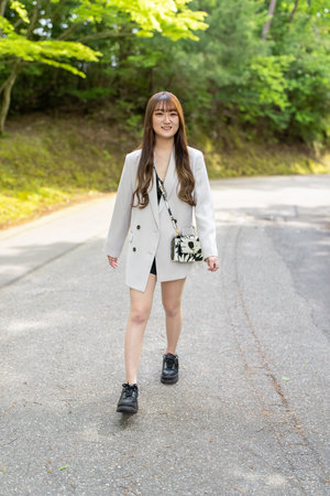 Portrait of a young beautiful woman walking on a road in the parkの写真素材