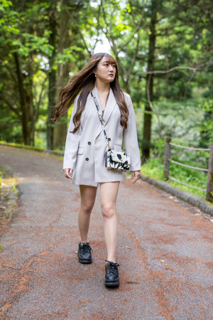 Young beautiful asian woman walking in the park and looking at cameraの写真素材