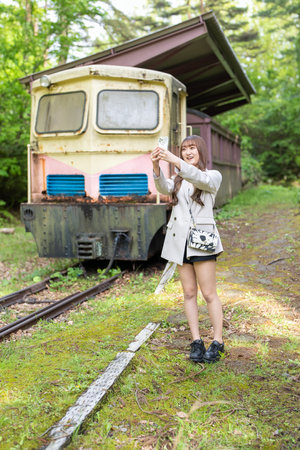 Young woman standing in front of an old train in the countryside.の写真素材