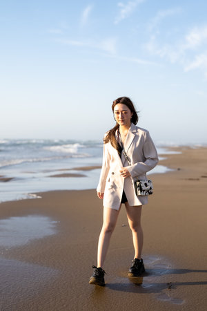 View of a beautiful girl in fashion clothing walking on the beach.の写真素材