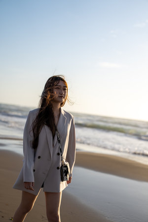 Portrait of a beautiful young woman walking on the beach at sunsetの写真素材