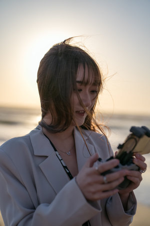 Beautiful asian woman playing video game on the beach at sunsetの写真素材