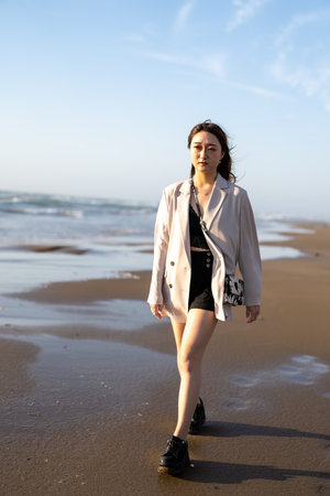 View of a beautiful girl in fashion clothing walking on the beach.の写真素材