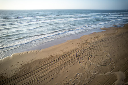 Sunset at the beach with a drawing in the sand and wavesの写真素材