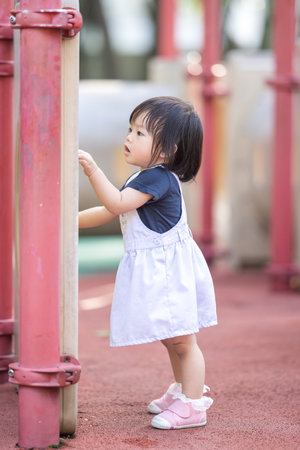 A one-year-old Chinese Malaysian girl playing on the children's playground equipment at KLCC Park in Kuala Lumpur City Centre, Malaysia.の写真素材
